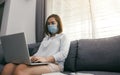 Asian woman working from home at a laptop computer during a coronavirus epidemic by quarantine and wearing medical masks Royalty Free Stock Photo