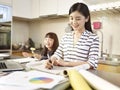 Asian woman working at home while taking care of daughter