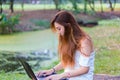 Asian woman working on a laptop at a garden or park