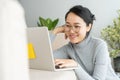Asian woman is working on a laptop in home . On her face are smile when she work at sofa Royalty Free Stock Photo