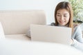 Asian woman is working on laptop in the living room. She sit on the floor and sofa is office desk Royalty Free Stock Photo