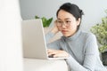 Asian woman is working  a laptop in the living room. She sit on the floor and sofa is office desk Royalty Free Stock Photo