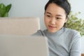 Asian woman is working on laptop in the living room. She sit on the floor and sofa is office desk. On her face are smile and Royalty Free Stock Photo