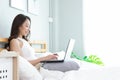 Asian woman working on a laptop sitting on the bed in the house Royalty Free Stock Photo