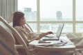 Asian woman is working with a notebook while she is sick and admit at patient`s bed in hospital. Work life not balance concept Royalty Free Stock Photo