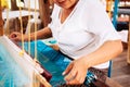 Asian Woman working on Vintage Laos style wooden weaving loom with silk fiber