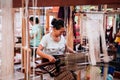 Asian Woman working on Vintage Laos style wooden weaving loom with silk fiber