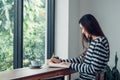 Asian woman writing book listening music with mobile sitting at cafe restaurant near window see through garden.lifestyle,Working Royalty Free Stock Photo