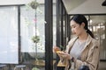 Asian woman writing information on sticky notes while standing in creative office. Royalty Free Stock Photo