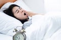 Asian woman yawning in bed feeling sleepy and tired lazy to wake up in morning, Royalty Free Stock Photo