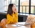Asian woman yawning due to overworking and exhausting. Young lady in bright yellow jumper