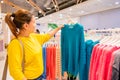 An Asian woman in yellow shirt is looking at a blue yarn shirt