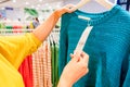 An Asian woman in yellow shirt is looking at a blue yarn shirt