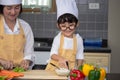 Asian woman young mother with son boy cooking salad food with vegetable holding tomatoes and carrots, bell peppers on plate for Royalty Free Stock Photo