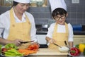 Asian woman young mother with son boy cooking salad mom sliced vegetables food son tasting salad dressing vegetable carrots and Royalty Free Stock Photo