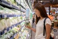 Asian womanin a supermarket is choosing green vegetables on the shelves, a concept of agriculture and a vegetarian diet Royalty Free Stock Photo