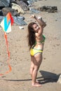 Asian women in bikini are playing colorful kite for fun on the beach.