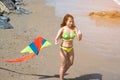 Asian women in bikini are playing colorful kite for fun on the beach.