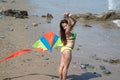 Asian women in bikini are playing colorful kite for fun on the beach.