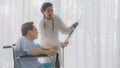 Asian woman doctor gives advice on x-ray film to an elderly old senior patient sit in wheelchair in Interior patient room Royalty Free Stock Photo