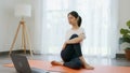 Asian women doing yoga exercises by themselves and watch video tutorials online from the laptop.