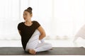 Asian women doing yoga seated twisting exercise at home, sitting in Lord of the Half Fishes Pose or Ardha Matsyendrasana, in white Royalty Free Stock Photo