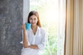 Asian women drinking coffee and wake up in her bed fully rested and open the curtains in the morning to get fresh air on sunshine Royalty Free Stock Photo