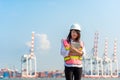 Asian women engineer holding laptop and working with container Cargo freight ship