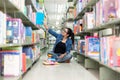 Asian women finding book and reading something in a book, adult female choosing a book on the bookshelf in a library.