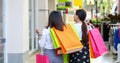 Asian women with friend are holding shopping bags and using a smart phone and smiling while doing shopping in the supermarket/mall Royalty Free Stock Photo