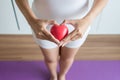 Asian woman hands holding red heart model on crotch with leucorrhoea