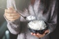 Asian women holding cooked jasmine rice bowls with spoon. Wearing a gray sweater Royalty Free Stock Photo