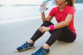 Asian women jogging workout on the beach. Sitting relax with and drinking water from the plastic bottles Royalty Free Stock Photo