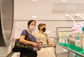 Asian women in protective mask standing on escalator in shopping mall.