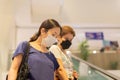 Asian women in protective mask standing on escalator in shopping mall. Royalty Free Stock Photo