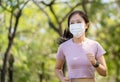 Asian women runners wears a Covid 19 protective mask and jogs in the garden in the morning. Health, sports and new normal concept Royalty Free Stock Photo
