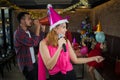 Asian woman singer in santa claus hat with a microphone singing and dancing in Christmas party and friend in restaurant. Royalty Free Stock Photo