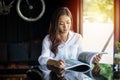 Asian women smiling and reading a book for relaxation at coffee shop Royalty Free Stock Photo