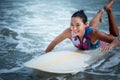 Asian women Surfboarding in the sea with small waves happily Royalty Free Stock Photo