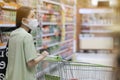 Asian women and surgical mask shopping some food in supermarket, covid-19 crisis Royalty Free Stock Photo