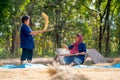 Asian woman with traditional clothes stand and winnow rice using basketry and other woman sit and hold some of rice grain beside