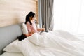 Asian woman using laptop while her daughter sleeping on bed Royalty Free Stock Photo