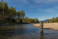 An asian women in waders, fishing a river in British Columbia, Canada