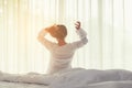 Asian women waking up stretching and raise arms in bed room at home. Young people early morning time and sunny day. Royalty Free Stock Photo