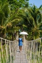 Asian women walking at a wooden bamboo rope bridge in the rainforest of Thailand