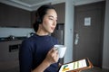 Asian women wearing headphone and using digital tablet video Conference and meeting and drinking coffee in The kitchen at the home Royalty Free Stock Photo