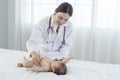 Asian woman who is a pediatrician Health check of sick newborn baby lying on white bed Royalty Free Stock Photo