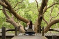 Asian women working and drinking coffee after education nature and forest input the laptop under big tree. The mangrove forest nur