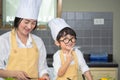 Asian woman young mother with son boy cooking salad food with vegetable holding tomatoes and carrots, bell peppers on plate for Royalty Free Stock Photo