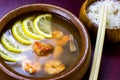 Asian wooden bowl with traditional light spicy thai cuisine rice and tom yam soup with shrimps, seafood and lemon on board